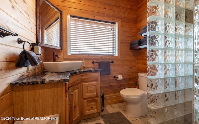 bathroom with tile patterned flooring, vanity, wood walls, and toilet