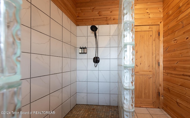 bathroom featuring wood ceiling, wood walls, a tile shower, and tile patterned floors