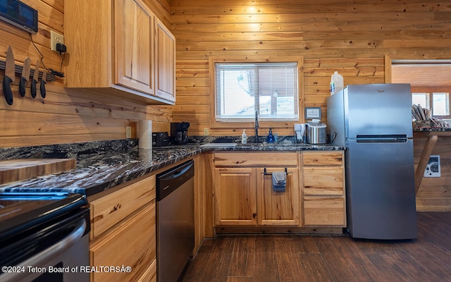 kitchen featuring dark stone countertops, wooden walls, a wealth of natural light, and stainless steel appliances