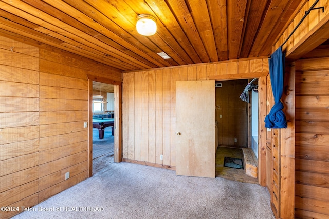 empty room featuring wood ceiling, light colored carpet, and wood walls