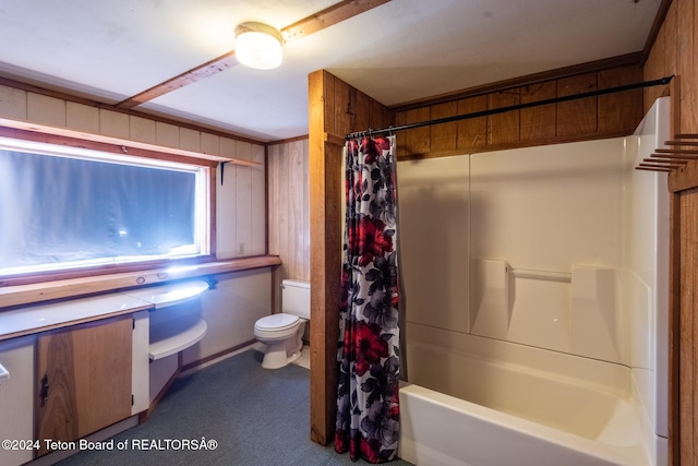 bathroom with shower / bath combo, toilet, and wood walls