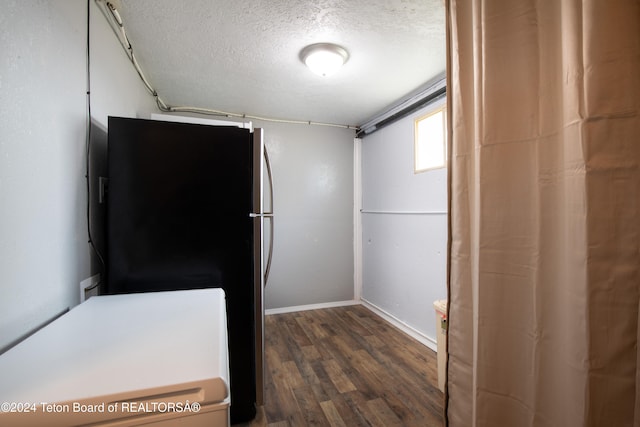 interior space with black fridge, a textured ceiling, and dark hardwood / wood-style flooring