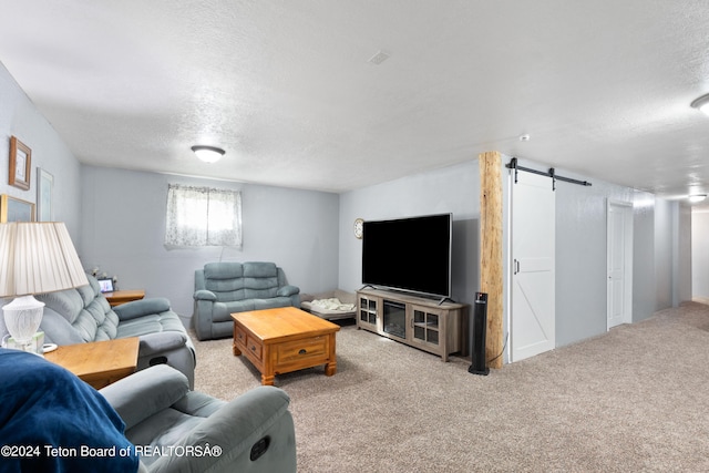 carpeted living room with a barn door and a textured ceiling