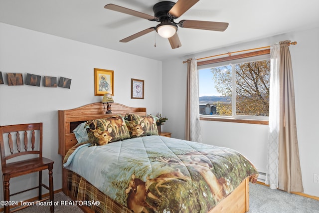 bedroom with light colored carpet, a baseboard heating unit, and ceiling fan