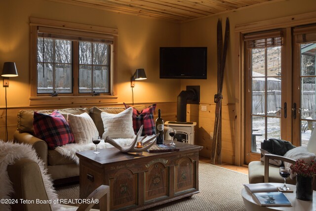 living room featuring french doors, a wood stove, light colored carpet, and wooden ceiling