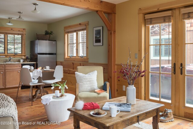 dining room with light hardwood / wood-style floors, beam ceiling, sink, and a wealth of natural light