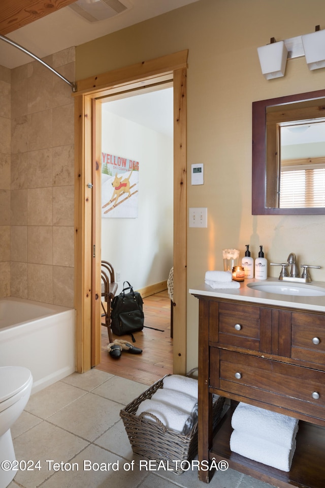 full bathroom featuring vanity, hardwood / wood-style floors, tiled shower / bath combo, and toilet