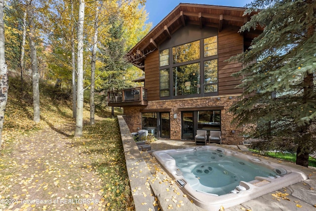 back of property featuring a patio, a balcony, and an outdoor hot tub