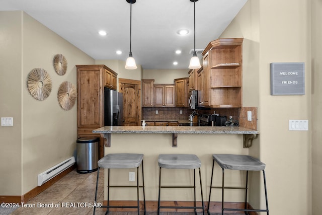 kitchen featuring decorative backsplash, a breakfast bar area, a baseboard radiator, appliances with stainless steel finishes, and light stone counters