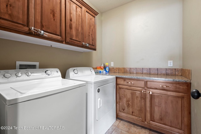 clothes washing area with washer and dryer, light tile patterned flooring, and cabinets