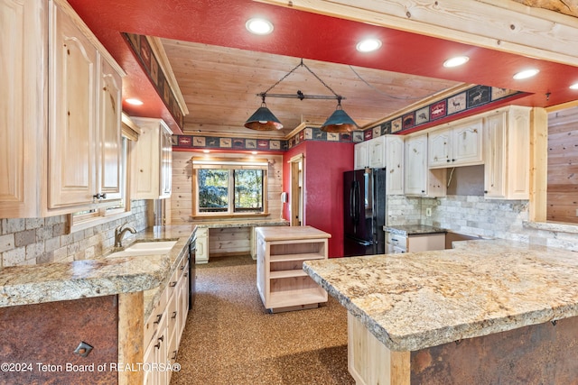 kitchen with decorative backsplash, black fridge, sink, light stone countertops, and wood walls