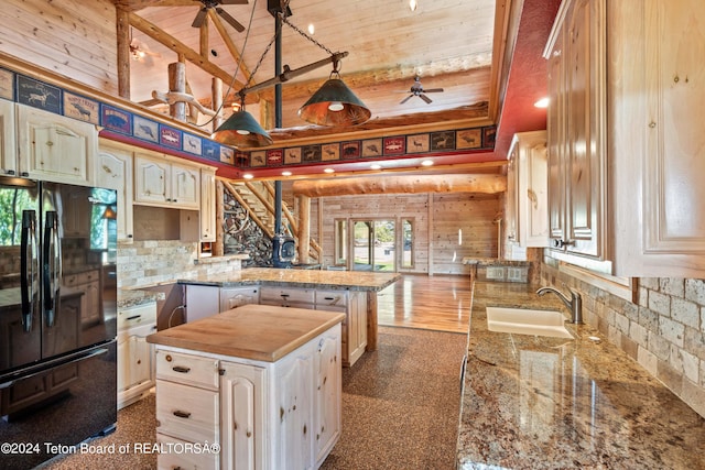 kitchen featuring kitchen peninsula, black fridge, vaulted ceiling, sink, and a center island