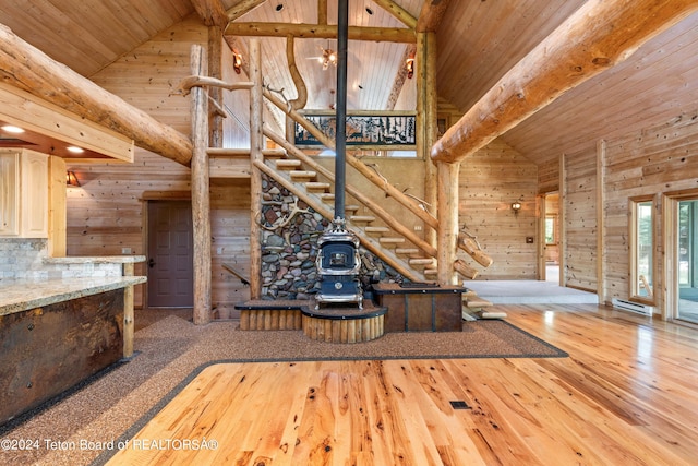 unfurnished living room with wood walls, high vaulted ceiling, light wood-type flooring, and wooden ceiling