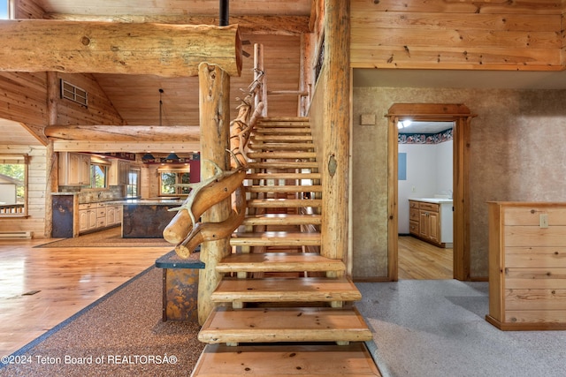 stairs featuring lofted ceiling, hardwood / wood-style floors, wooden ceiling, wood walls, and sink