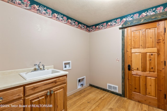 laundry room featuring light hardwood / wood-style floors, sink, washer hookup, and cabinets