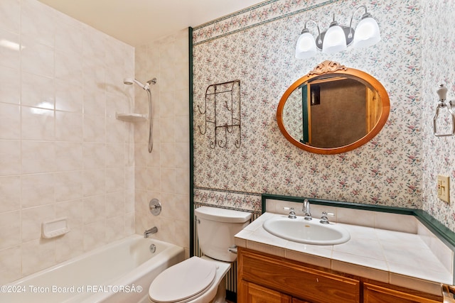 full bathroom with tiled shower / bath, vanity, and toilet