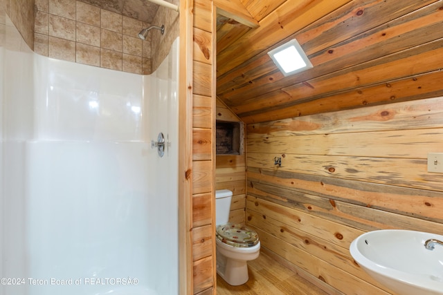 bathroom featuring sink, toilet, wooden walls, hardwood / wood-style flooring, and a shower