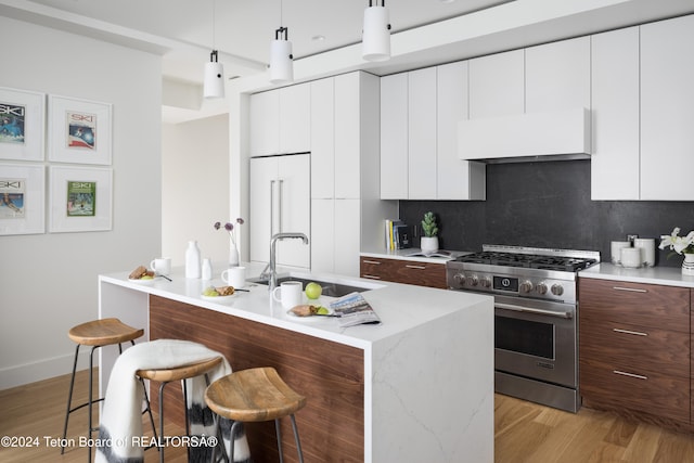 kitchen featuring a kitchen bar, pendant lighting, decorative backsplash, high end appliances, and ventilation hood