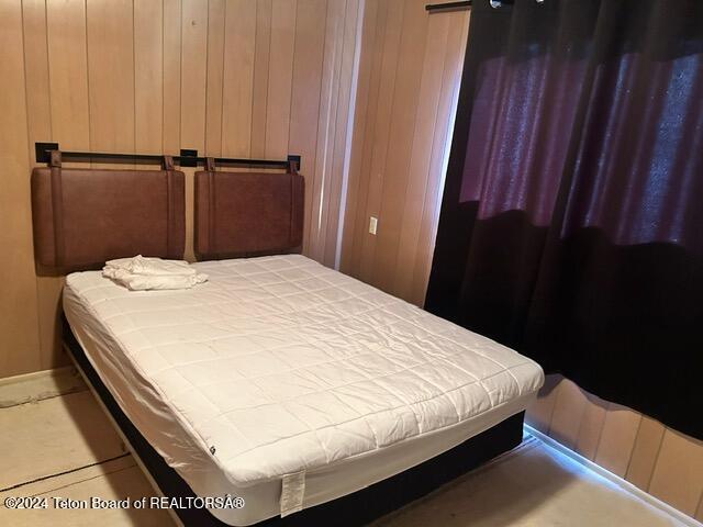 bedroom featuring wood walls