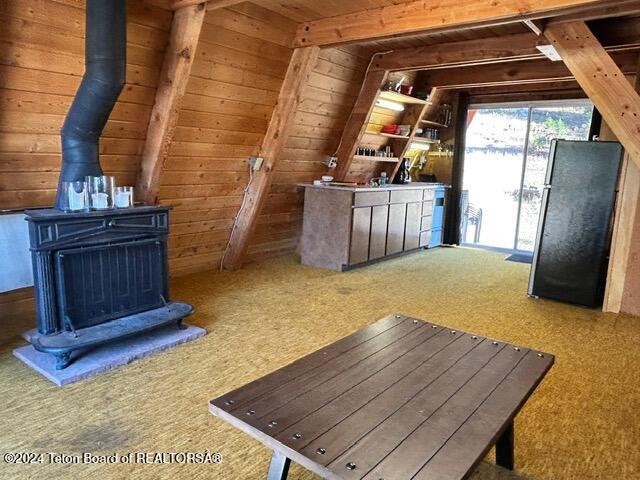 interior space with wood walls, wooden ceiling, black refrigerator, and carpet floors