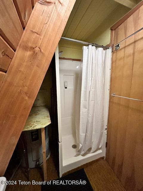 bathroom with wooden walls and a shower with shower curtain