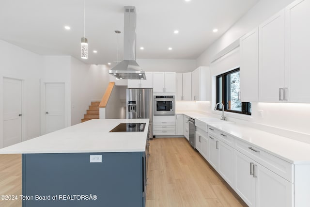 kitchen featuring a center island, white cabinets, light wood-type flooring, appliances with stainless steel finishes, and decorative light fixtures