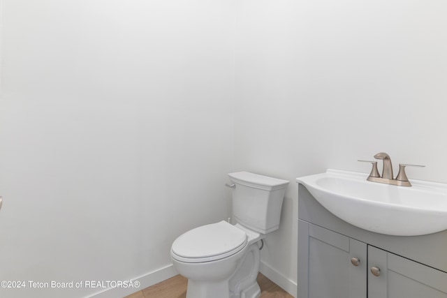 bathroom with wood-type flooring, vanity, and toilet