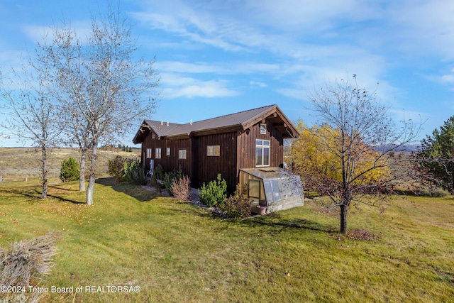 view of side of property with a lawn and a rural view