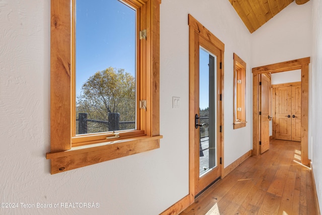 hallway with light hardwood / wood-style floors, lofted ceiling, and wood ceiling