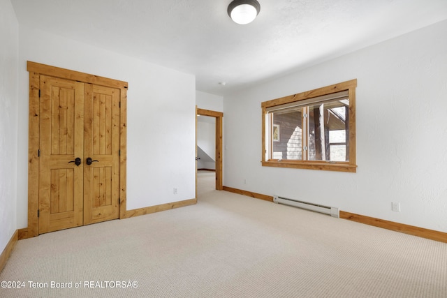 carpeted empty room featuring a baseboard heating unit