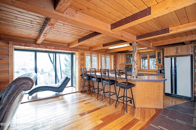 kitchen with wooden ceiling, hardwood / wood-style flooring, beamed ceiling, stainless steel counters, and white refrigerator