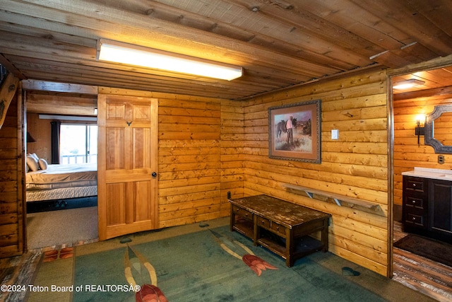 interior space featuring rustic walls, carpet, and wood ceiling