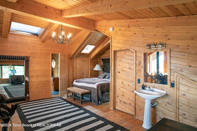 bedroom featuring wood ceiling, a chandelier, wooden walls, lofted ceiling with skylight, and light wood-type flooring