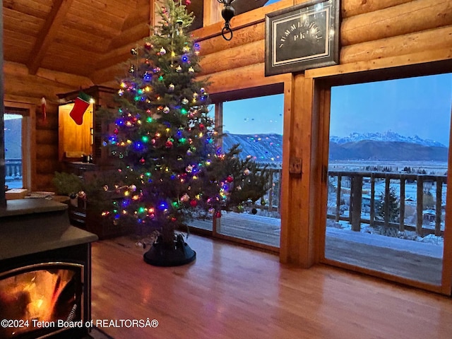 interior space featuring a mountain view, beam ceiling, hardwood / wood-style floors, wooden ceiling, and log walls