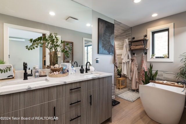 bathroom featuring a bathing tub, plenty of natural light, vanity, and hardwood / wood-style flooring