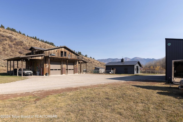 exterior space featuring a lawn, a carport, a mountain view, a garage, and an outbuilding