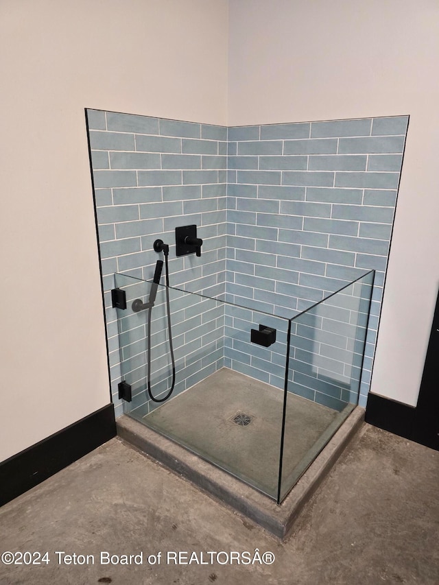 bathroom with tiled shower and concrete flooring