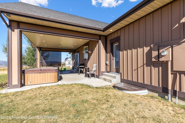 rear view of property featuring a hot tub, a patio area, and a yard