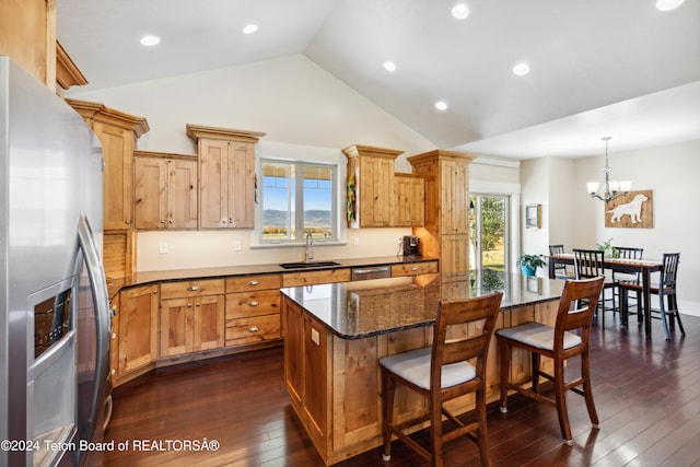 kitchen with stainless steel appliances, decorative light fixtures, sink, dark wood-type flooring, and a center island