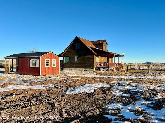 snow covered property with an outbuilding and a porch