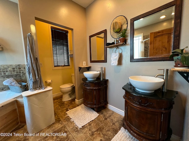 bathroom with toilet, vanity, and a relaxing tiled tub