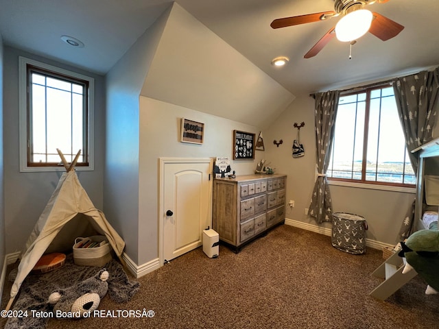 interior space with lofted ceiling, ceiling fan, and dark carpet