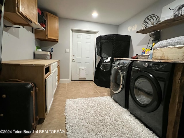 clothes washing area with cabinets, independent washer and dryer, and light tile patterned floors