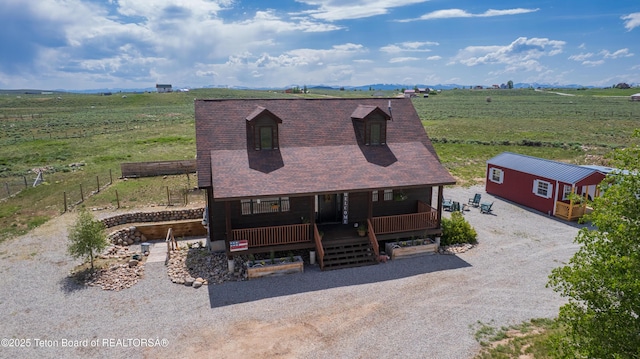 8 S Kicking Bird Rd, Pinedale, WY 82941 - view of front of home featuring covered porch, a view of countryside, gravel driveway, and a shingled roof