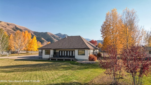 view of front of property with a deck with mountain view and a front lawn