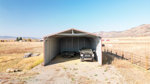 view of outdoor structure featuring a mountain view, a rural view, and a carport