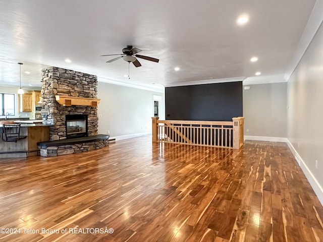 living room with hardwood / wood-style floors, ceiling fan, a fireplace, and crown molding