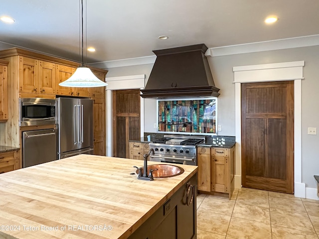 kitchen with high end appliances, sink, wooden counters, decorative light fixtures, and custom exhaust hood