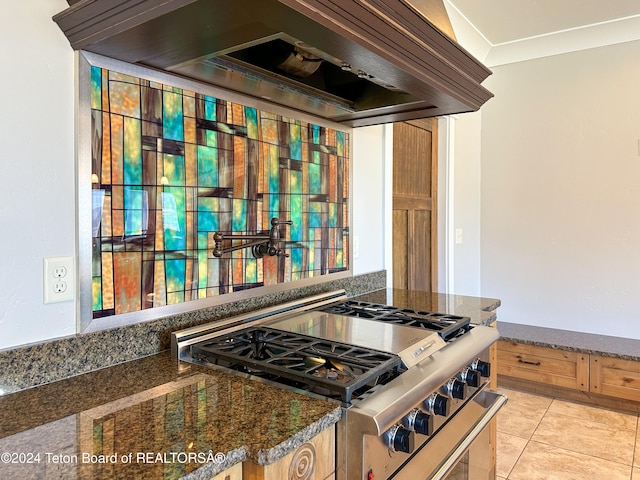 kitchen with premium range hood, crown molding, dark stone countertops, high end stove, and light tile patterned floors