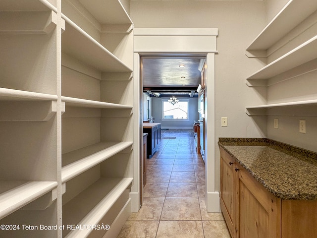 walk in closet featuring light tile patterned floors and an inviting chandelier